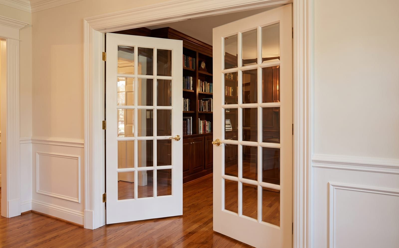 White-painted interior French doors with fifteen clear divided lites between a Ladue dining room and library