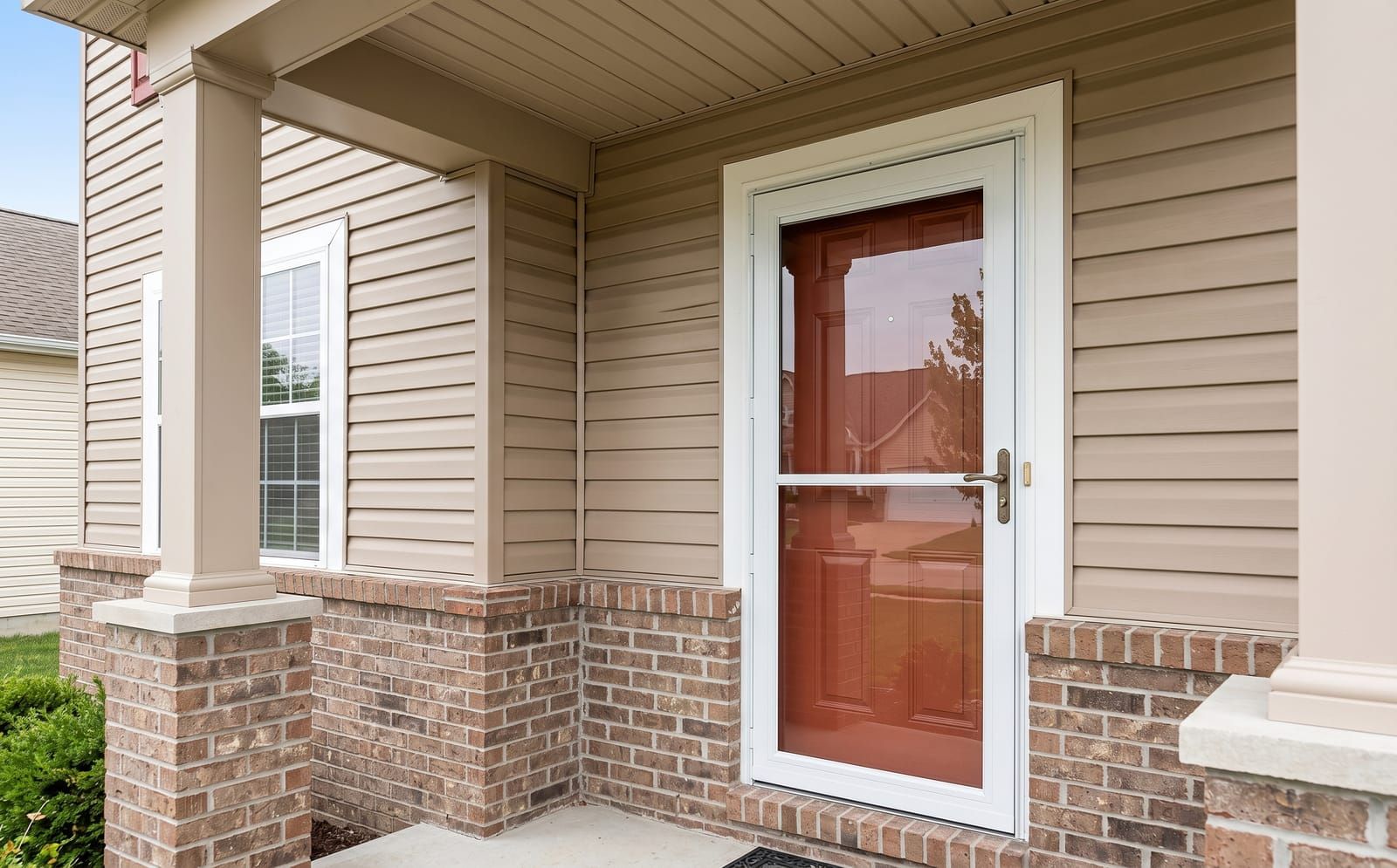 White aluminum full-view storm door with retractable screen over a brick-red main entry on a St. Charles two-story home
