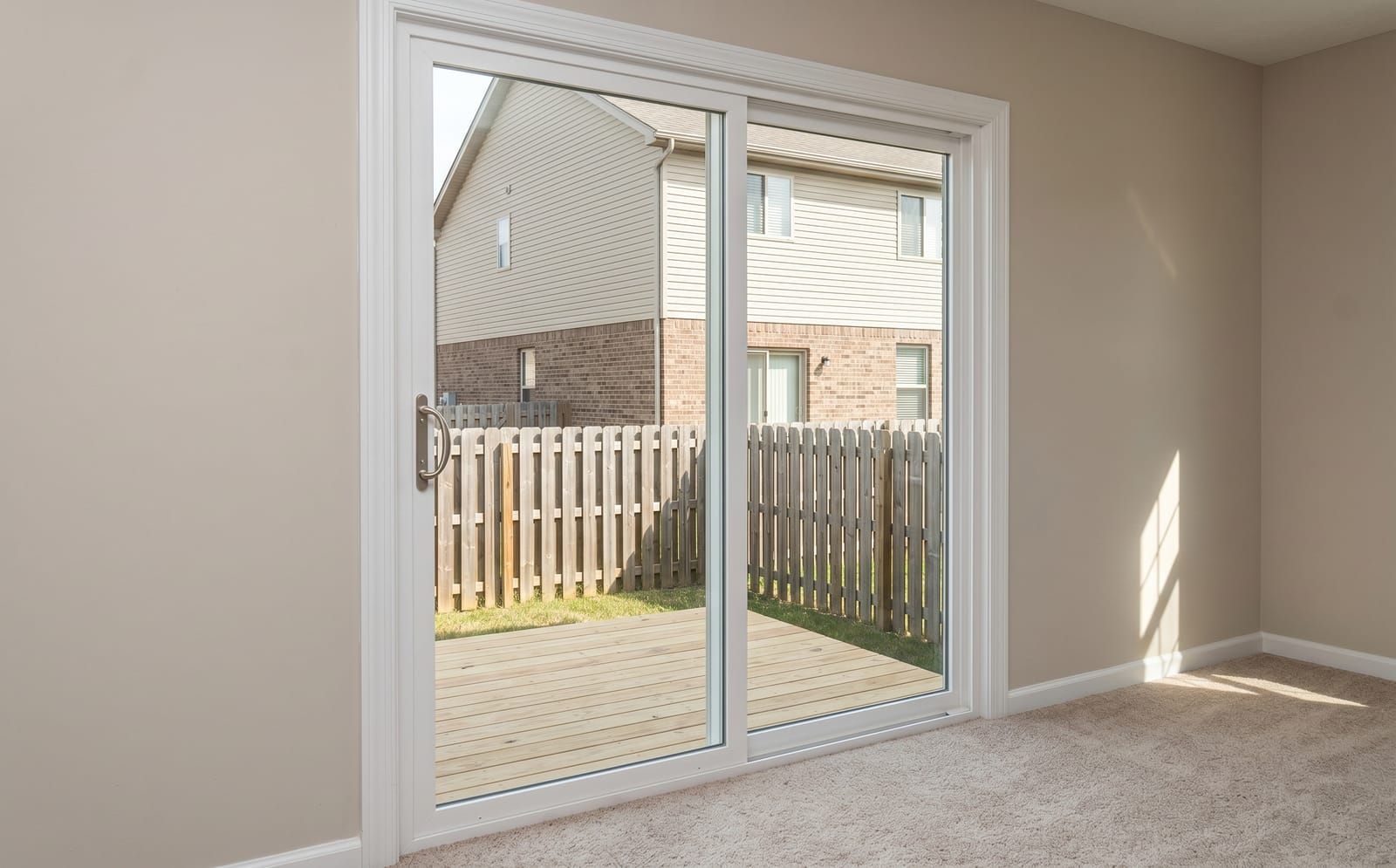 White-vinyl 2-panel sliding patio door on the back of a St. Charles two-story home opening to a wood deck