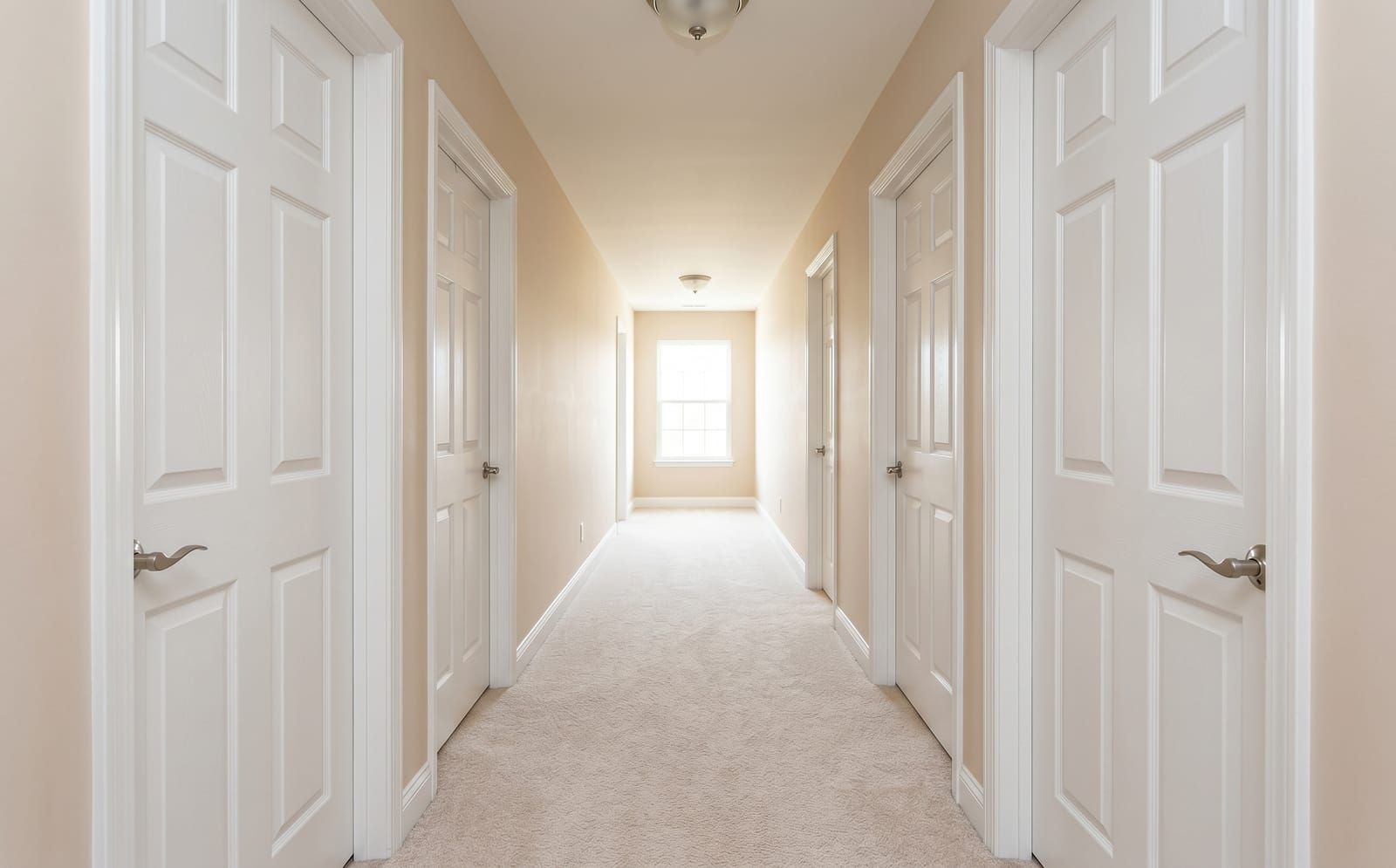 Long hallway in a St. Peters home with five matching white solid-core six-panel interior doors and brushed-nickel levers